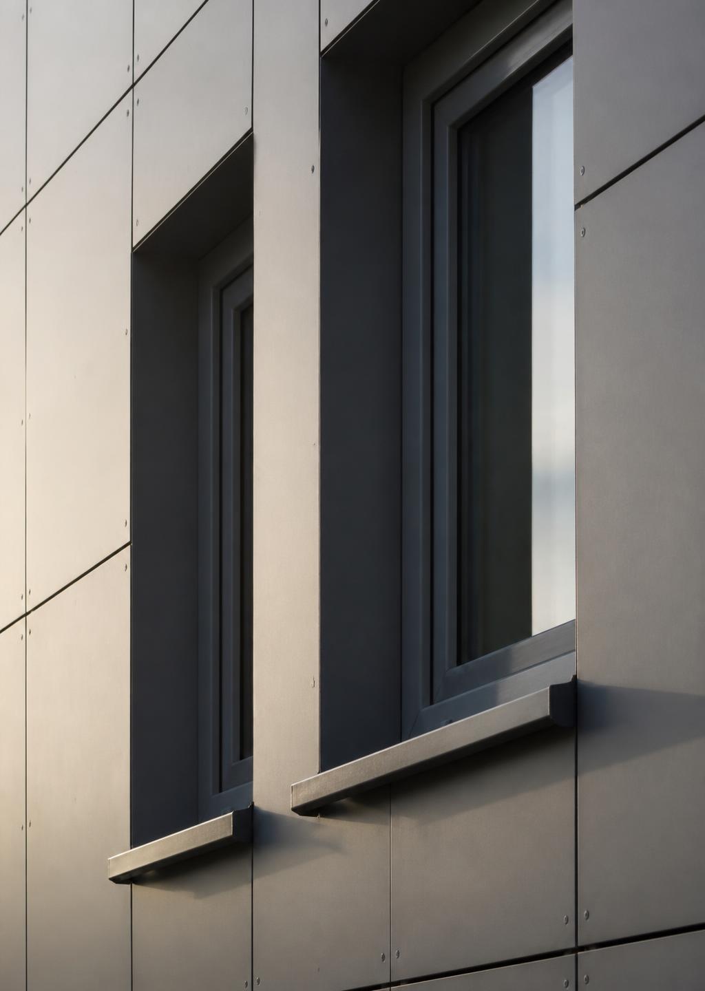 Modern building facade with window frames, metal cills and cladding panels